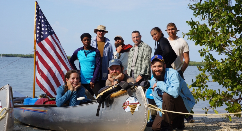 a group of veterans gathers around a canoe with an american flag 